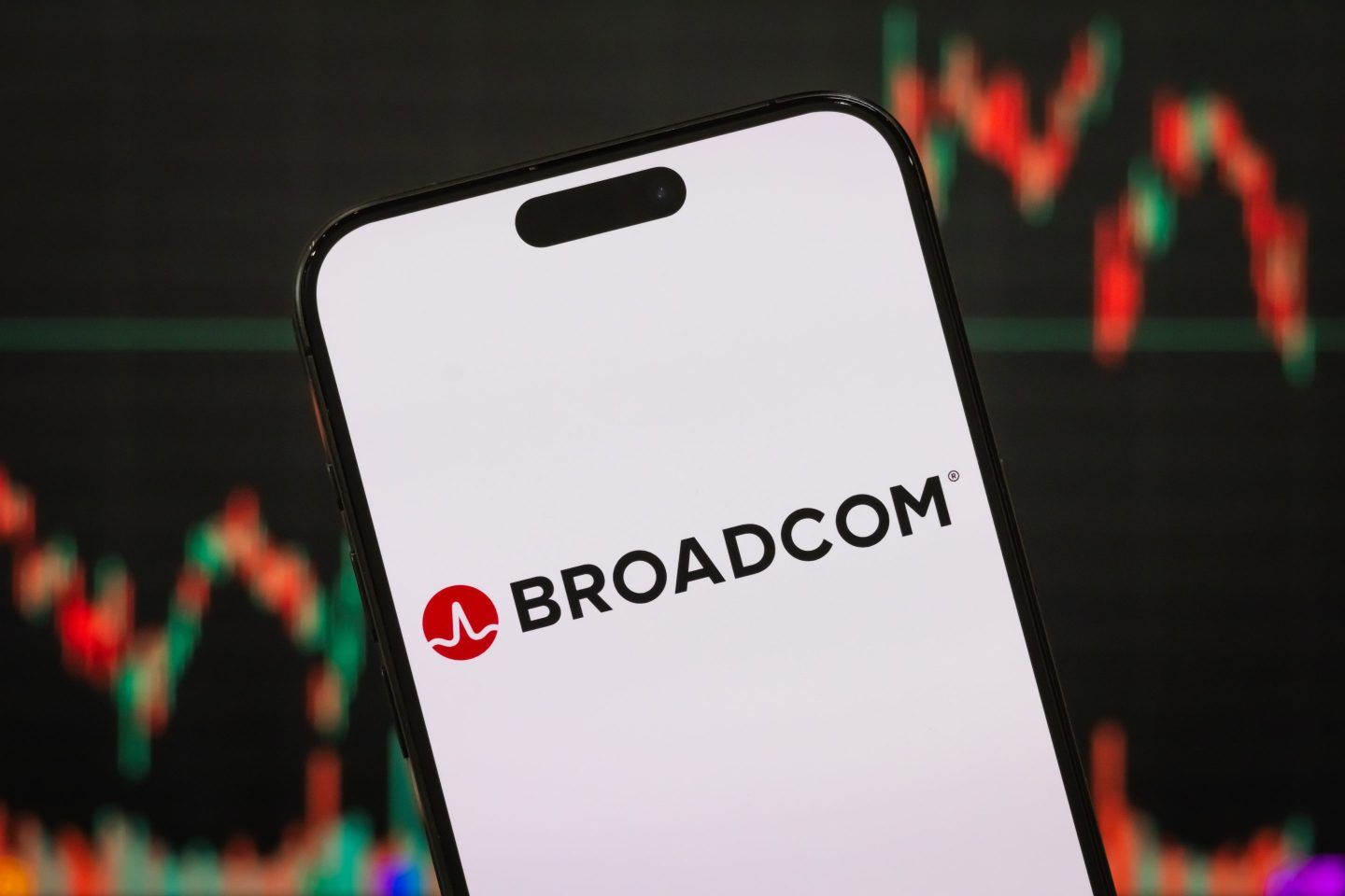 In this photo illustration, the Broadcom Inc. logo is displayed on a smartphone screen, with the company's latest stock market performance and candlestick charts visible in the background.