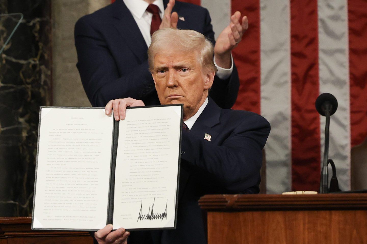 President Donald Trump shows an executive order he signed in March.