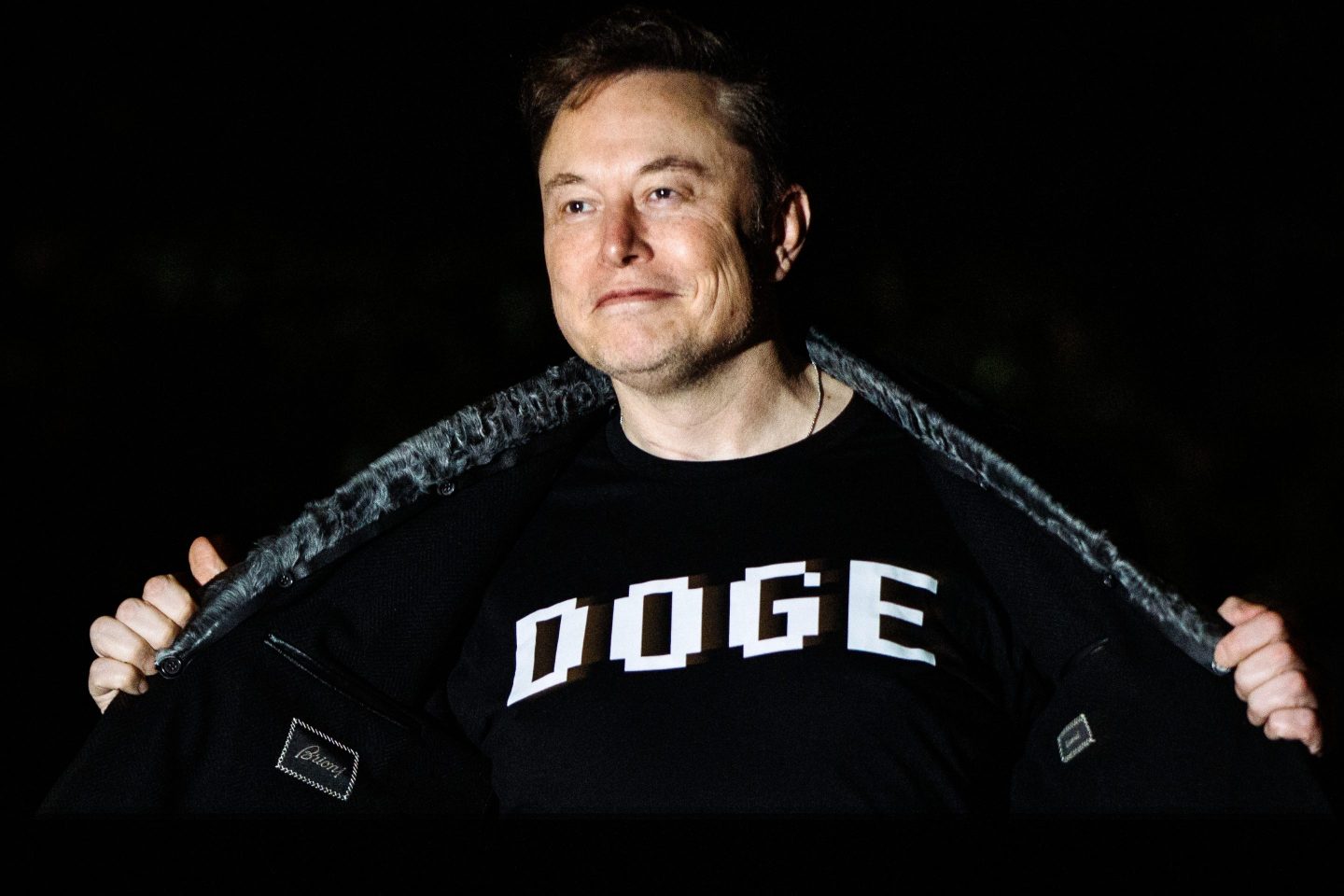 Elon Musk wearing a t-shirt with DOGE written on it.
