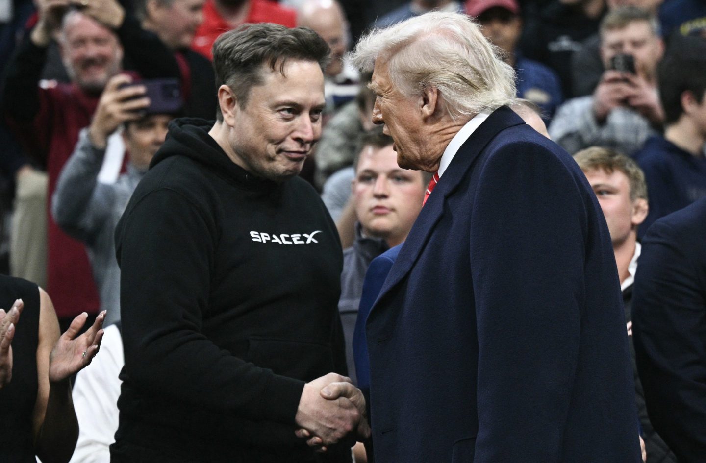 Tesla and SpaceX CEO Elon Musk and US President Donald Trump shake hands as they attend the men's NCAA wrestling competition.