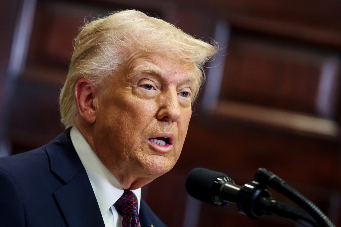 Donald Trump speaks at a podium in late March.
