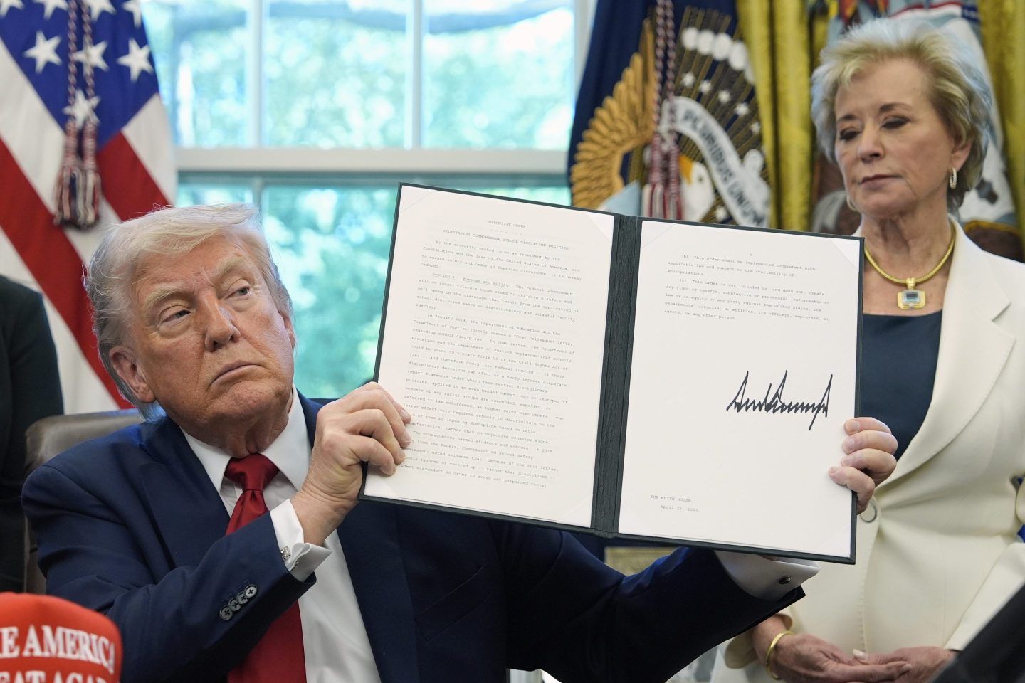 President Donald Trump holds a signed an executive order relating to school discipline policies as Education Secretary Linda McMahon listens in the Oval Office of the White House, on April 23, 2025.