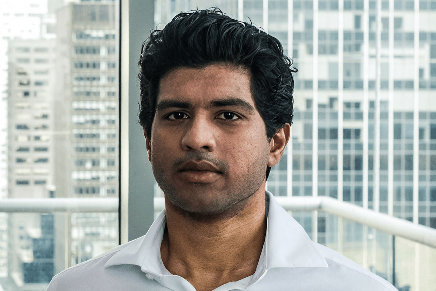 Abhi Pingle looks into the camera in front of an office window.