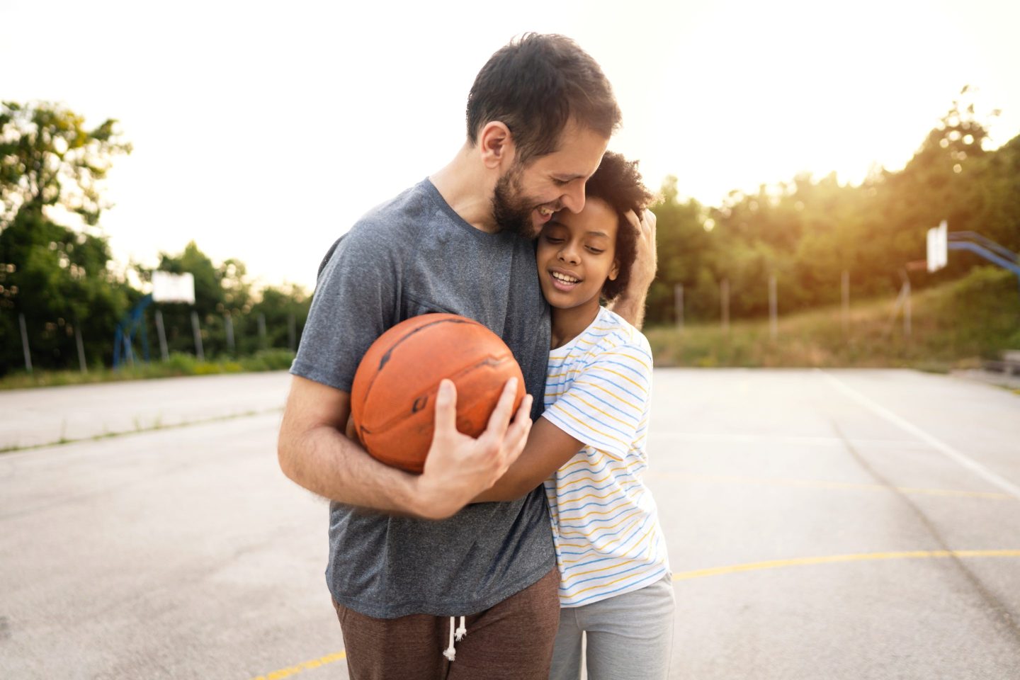 Father with one arm around daughter and another holding a basketball