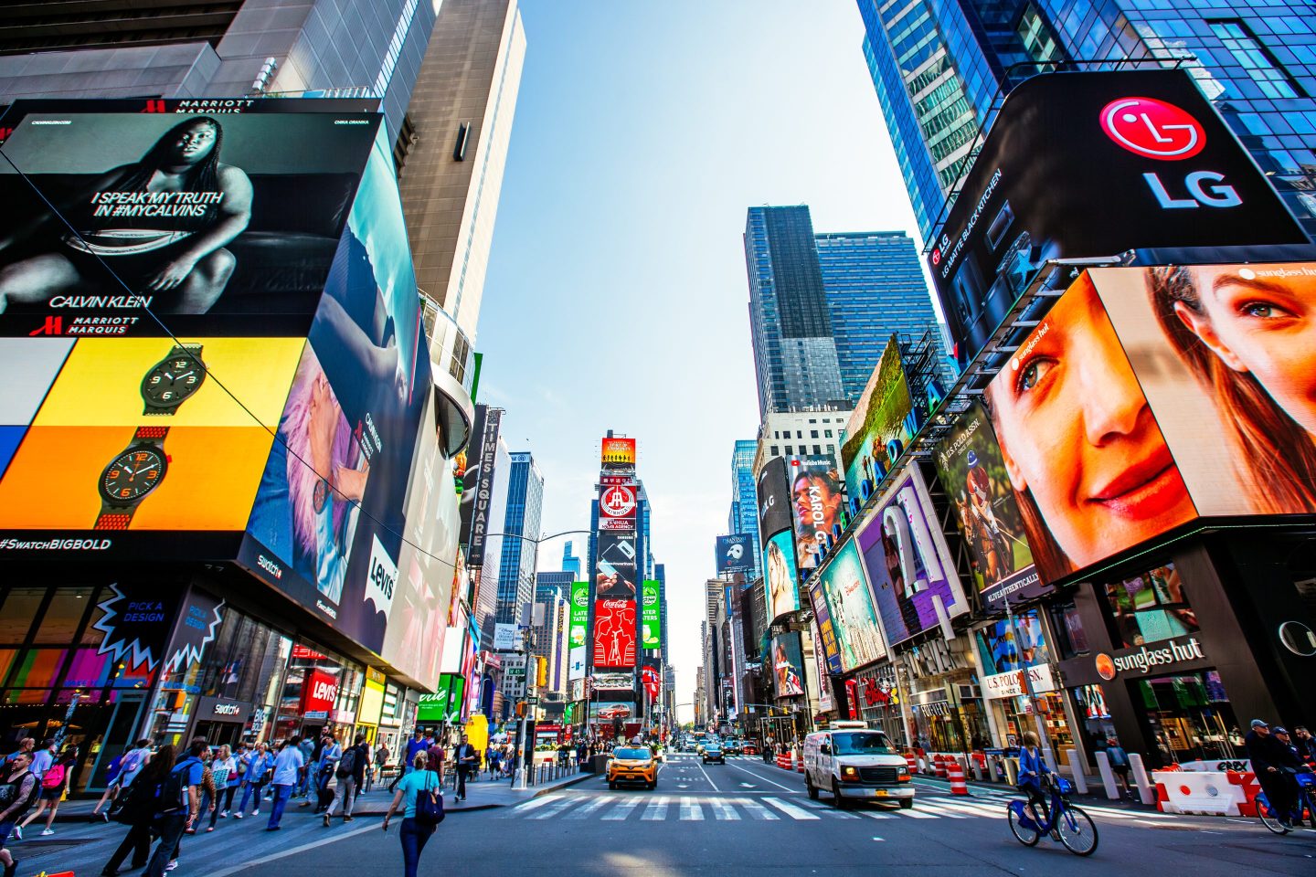 Crowded Times Square with multiple ads on a sunny day with clear blue sky, wide angle view, New York, USA
