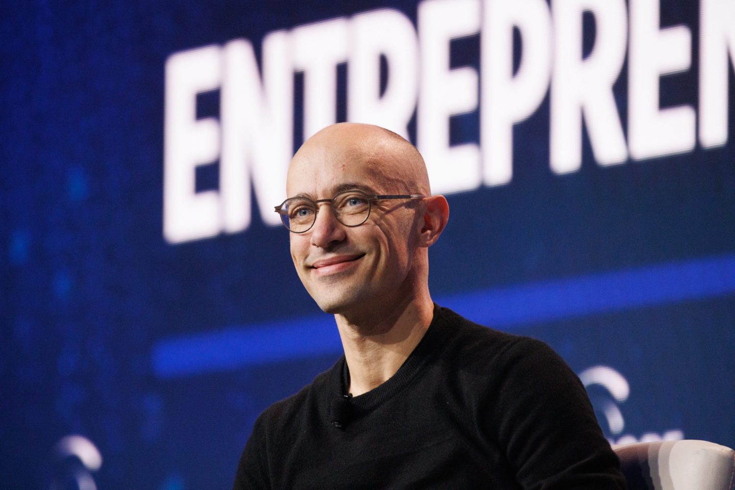 Tobias Lutke, founder and chief executive officer of Shopify speaking on a stage in front of a blue background.