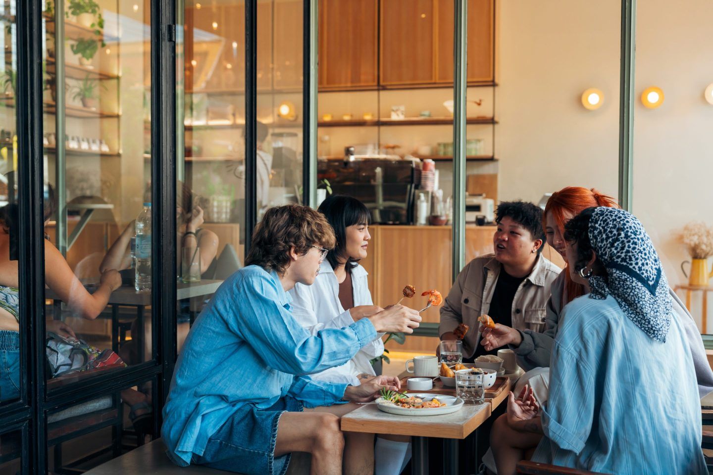 Group of diverse friends laughing and sharing breakfast at a cafe