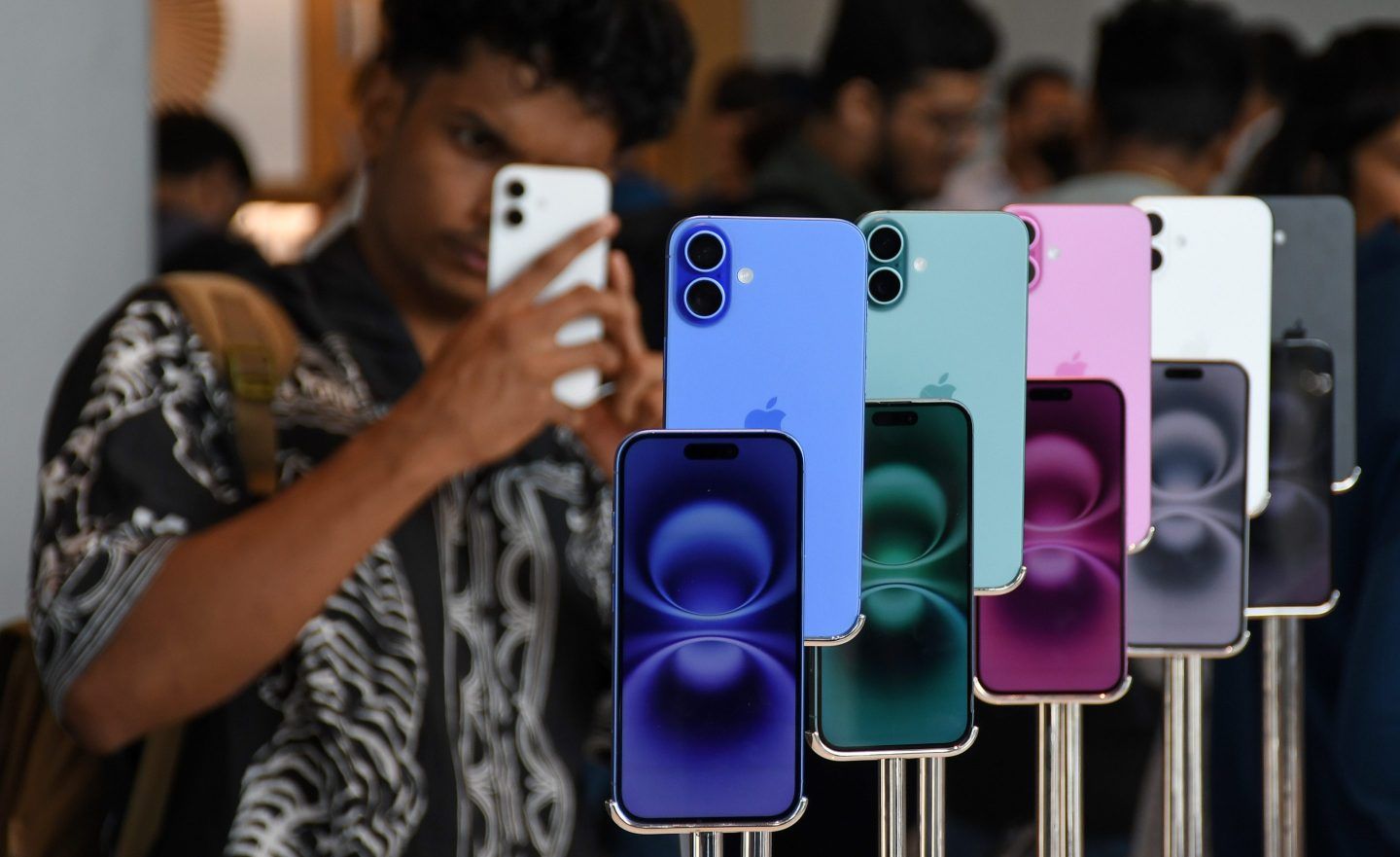 A man seen using his phone next to iPhone 16 models kept on display at the Apple store in Bandra Kurla Complex (BKC) in Mumbai. 