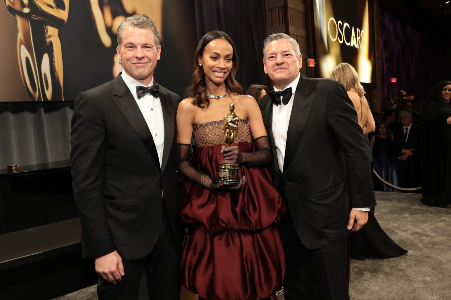 Netflix CEOs Greg Peters and Ted Sarandos with Zoe Saldaña at the 97th Annual Oscars Governors Ball
