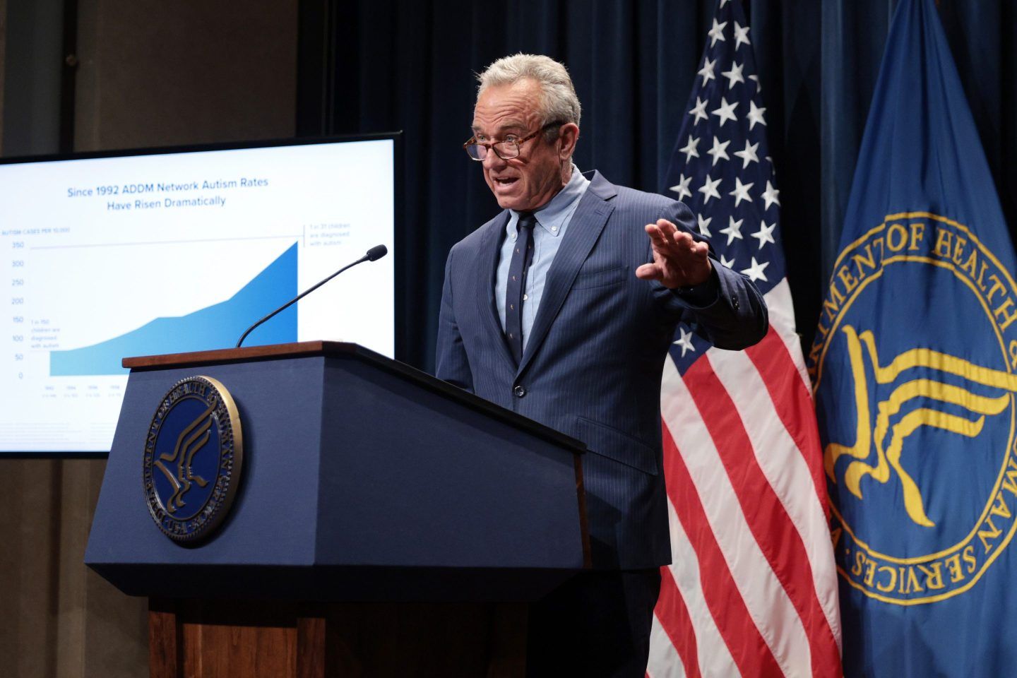 RFK Jr. speaks at a lectern in front of an American flag