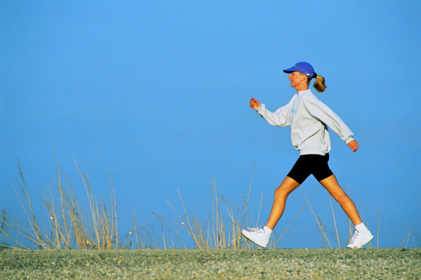 Woman walking briskly against blue sky