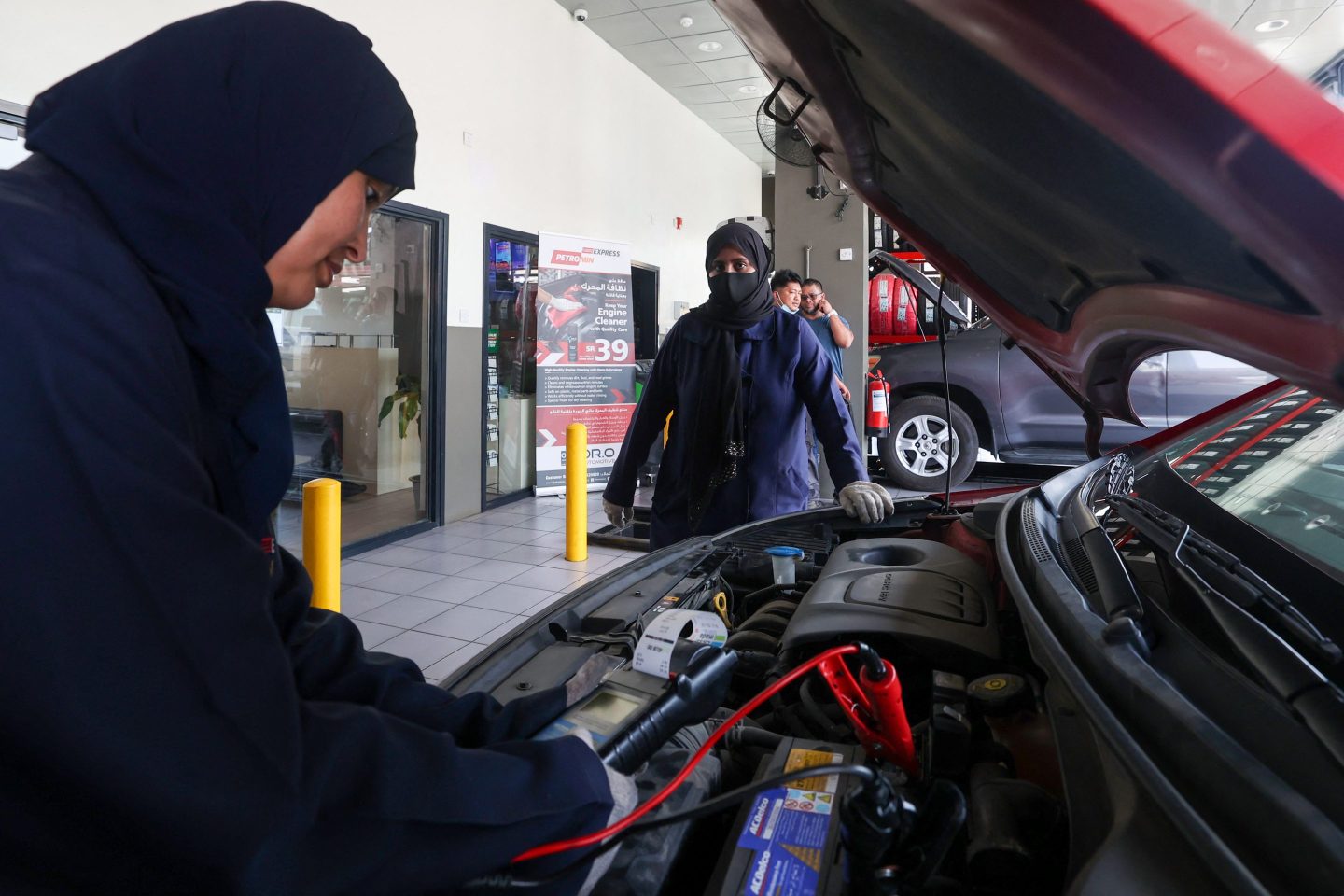 Two women work at an auto repair shop in Saudi Arabia.
