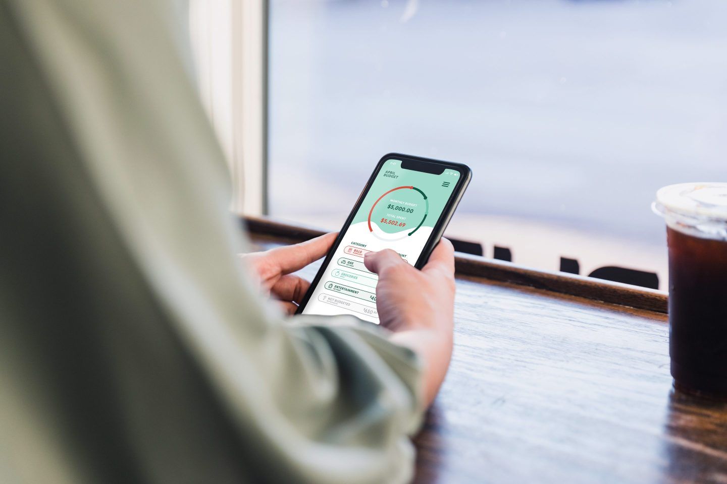 A person looking at their banking app in a coffee shop.