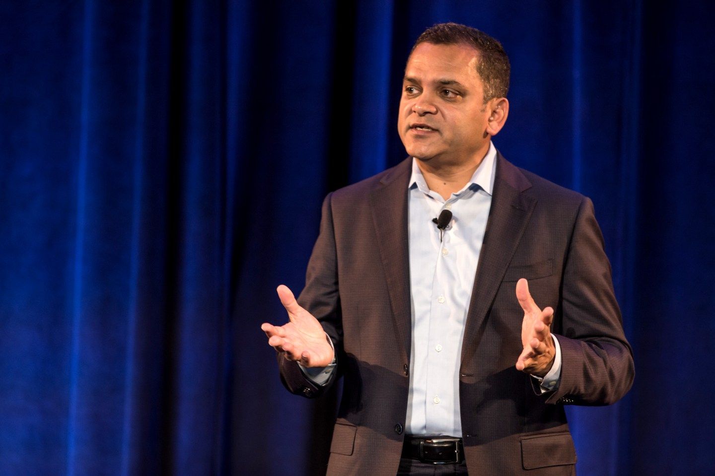 Tarang Amin speaks in front of a blue curtain.