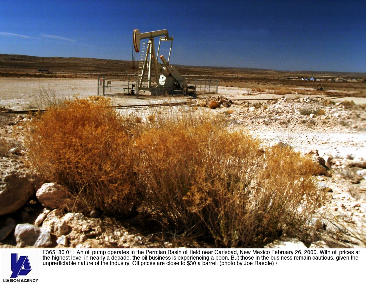 A pumpjack slowly nods up and down in New Mexico's desert Permian Basin landscape.