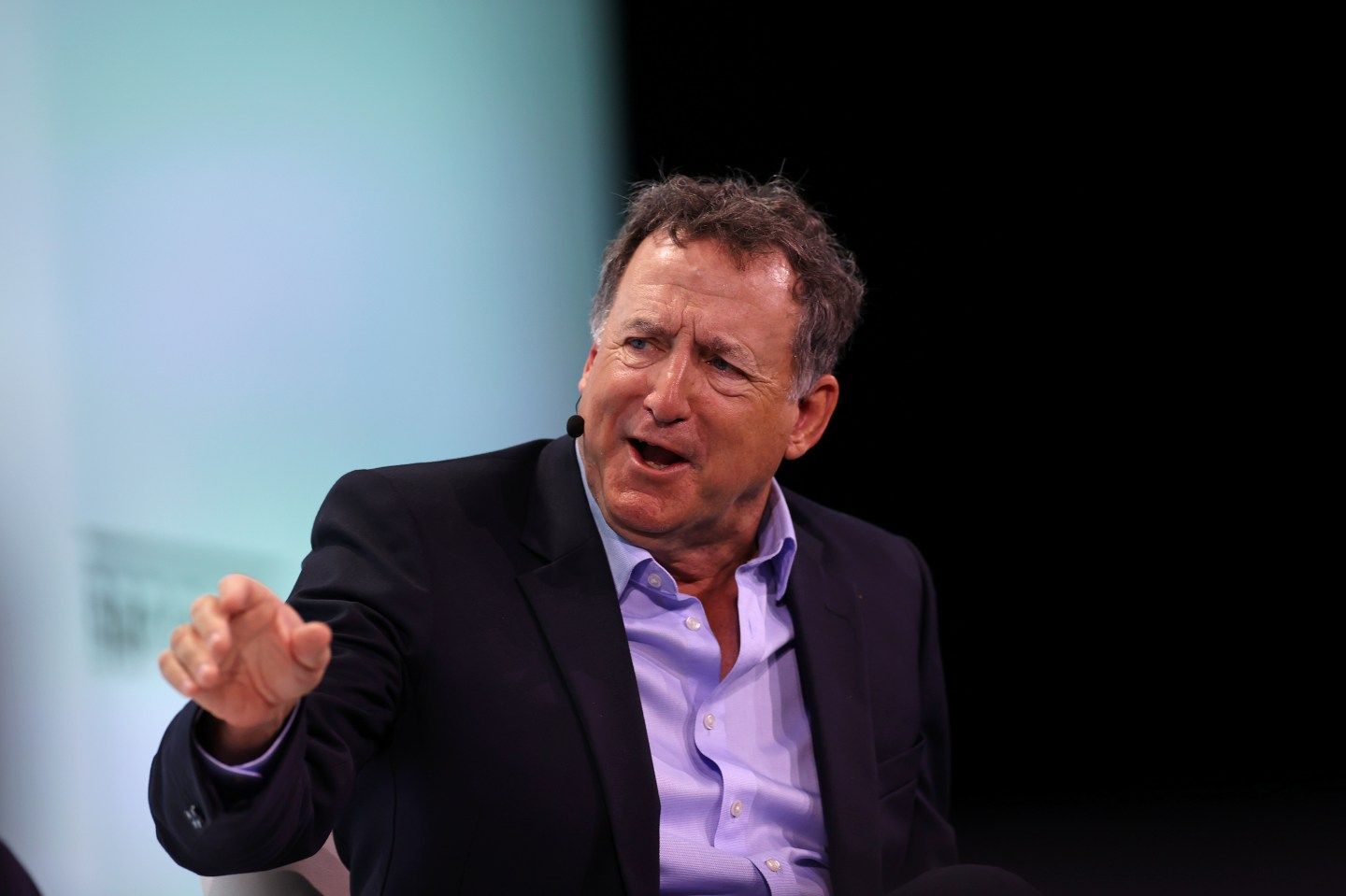 NRG chairman Larry Coben speaks while seated, extending his arm for effect, at the CERAWeek energy conference in Houston.
