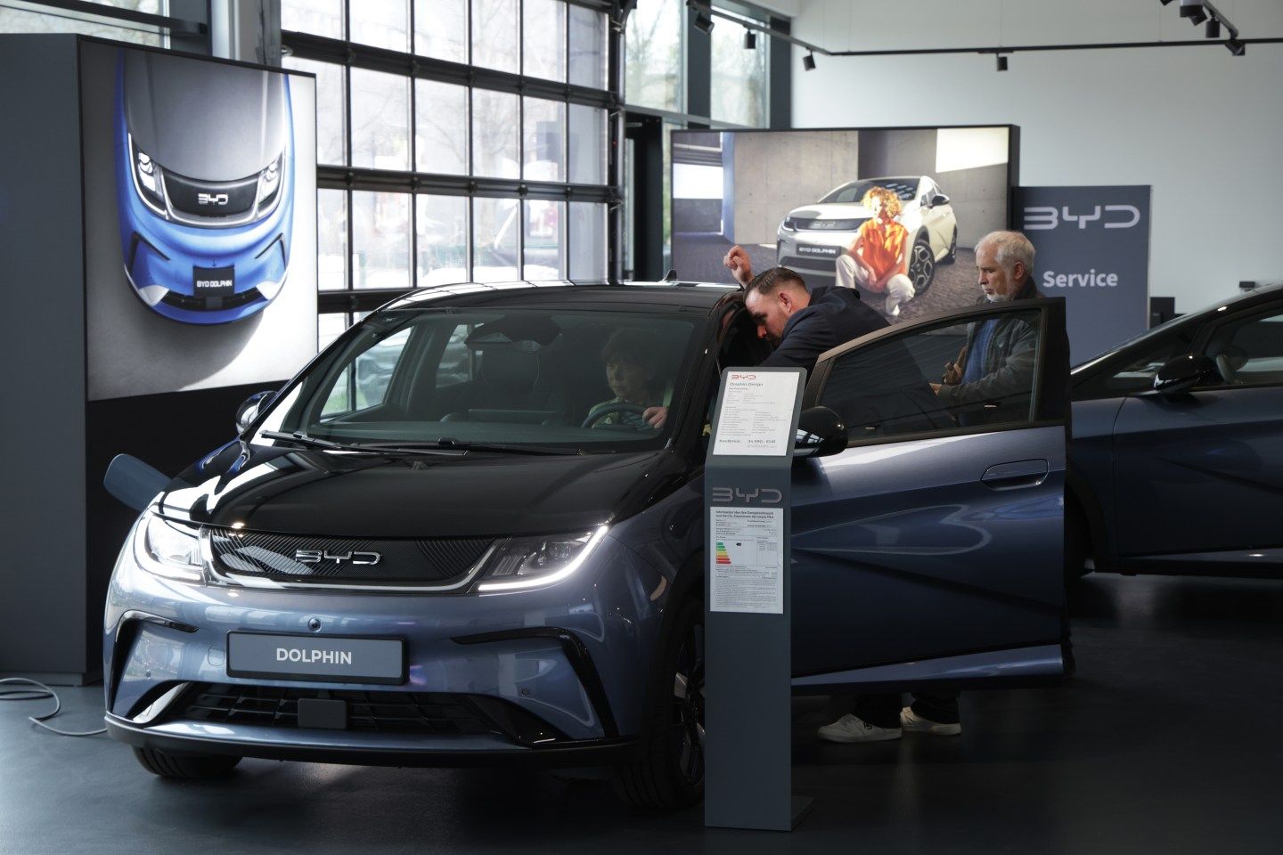 Potential customers inspect a new BYD vehicle on a showroom floor.