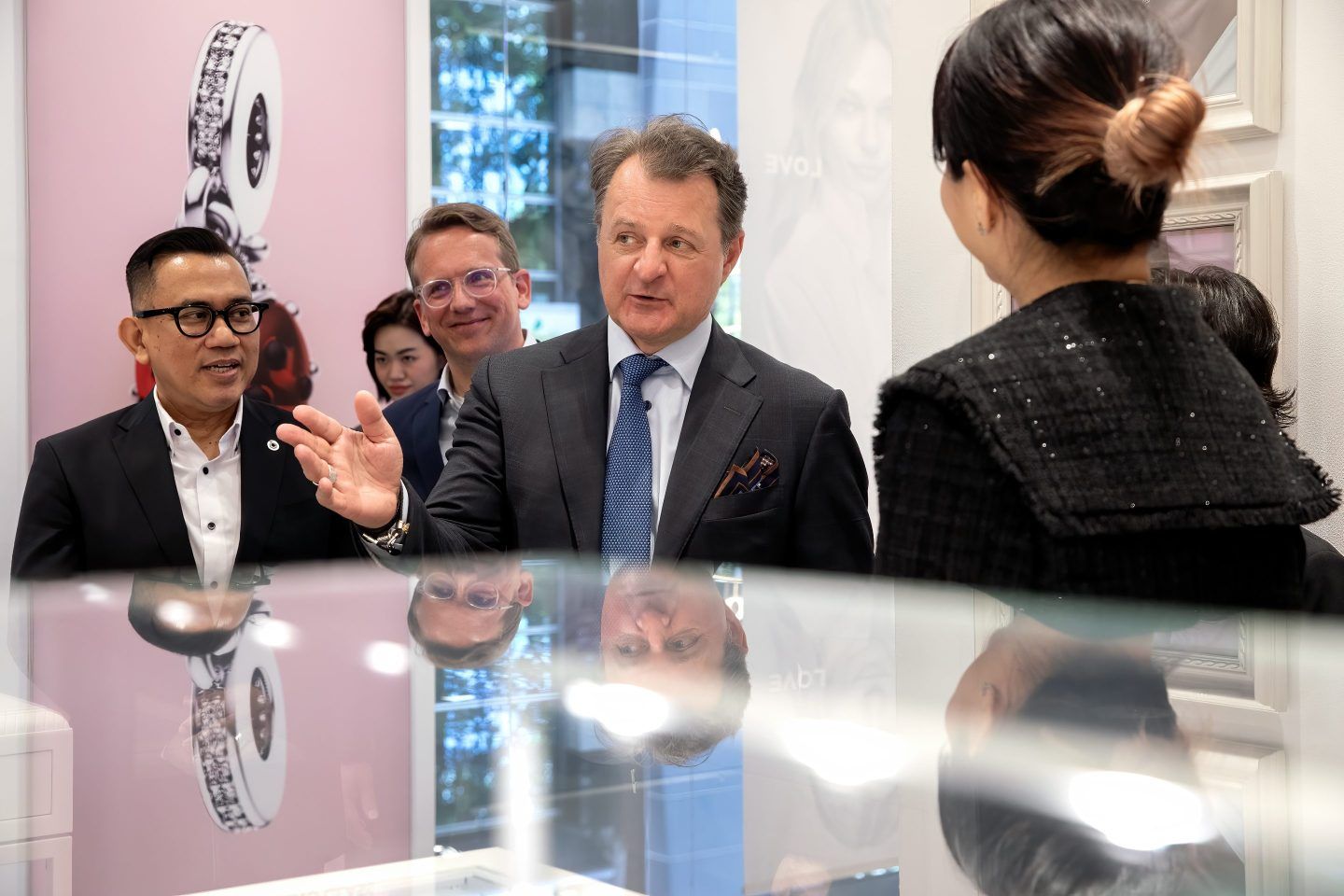 Alexander Lacik stands over a display case and has a group of people around him, listening to him speak.