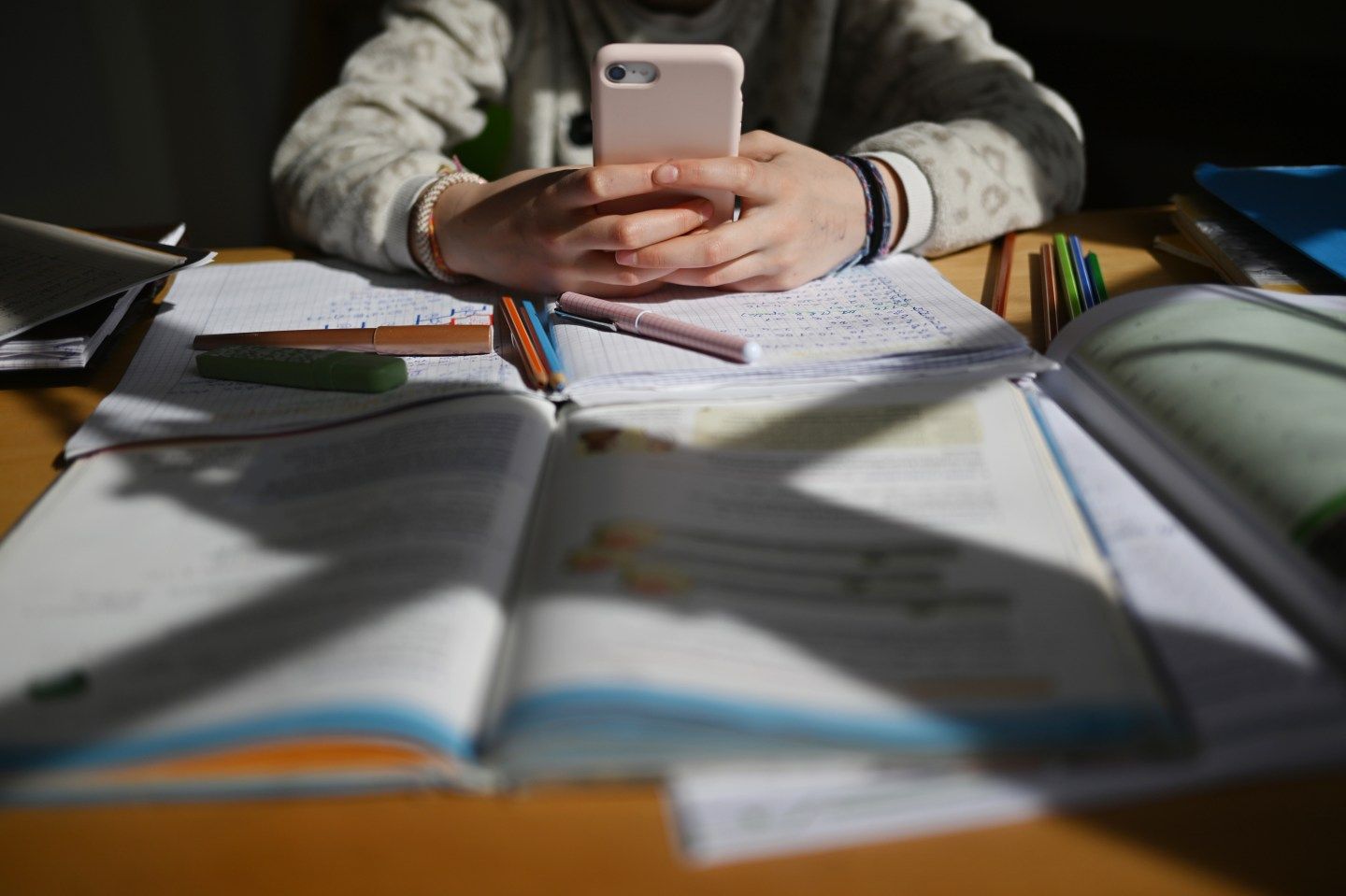 Child holds a phone over their homework.