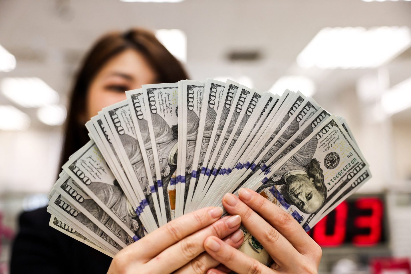 A bank employee poses with $100 notes in Taipei on May 6, 2025. 