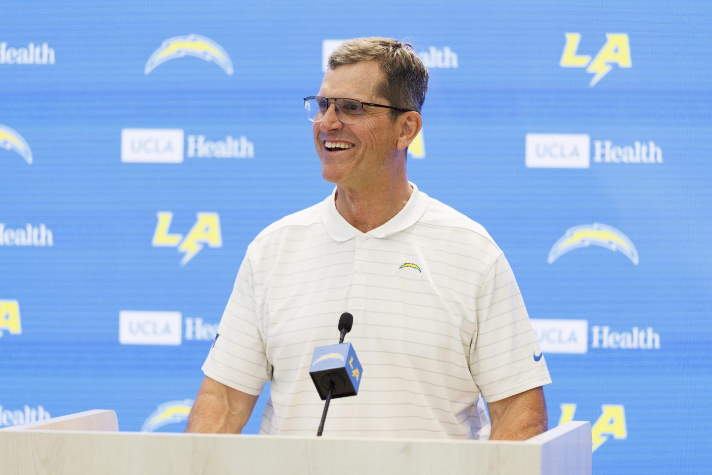 LA Chargers head coach Jim Harbaugh speaks in front of a podium