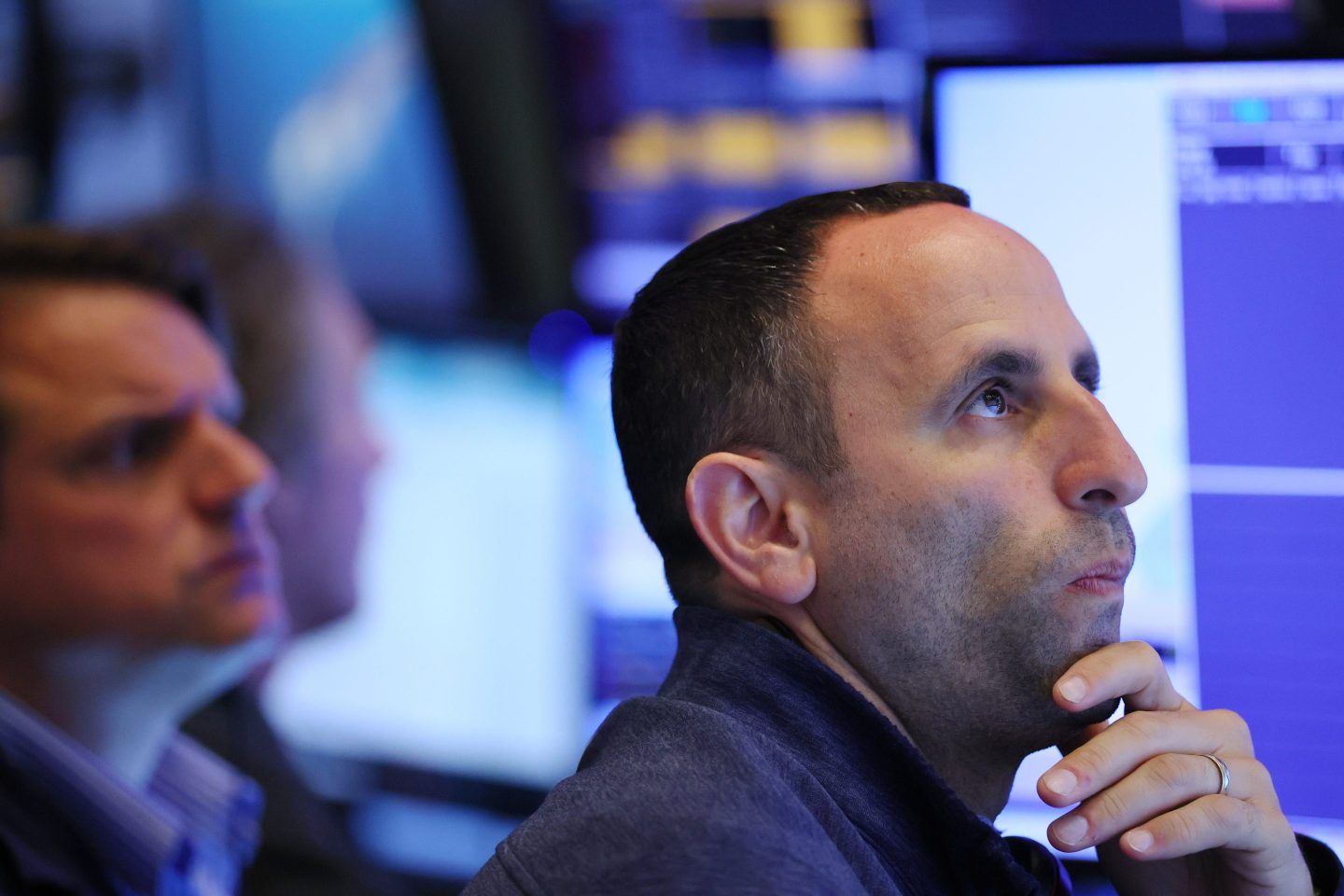 A stock market traders looks at screen worried.