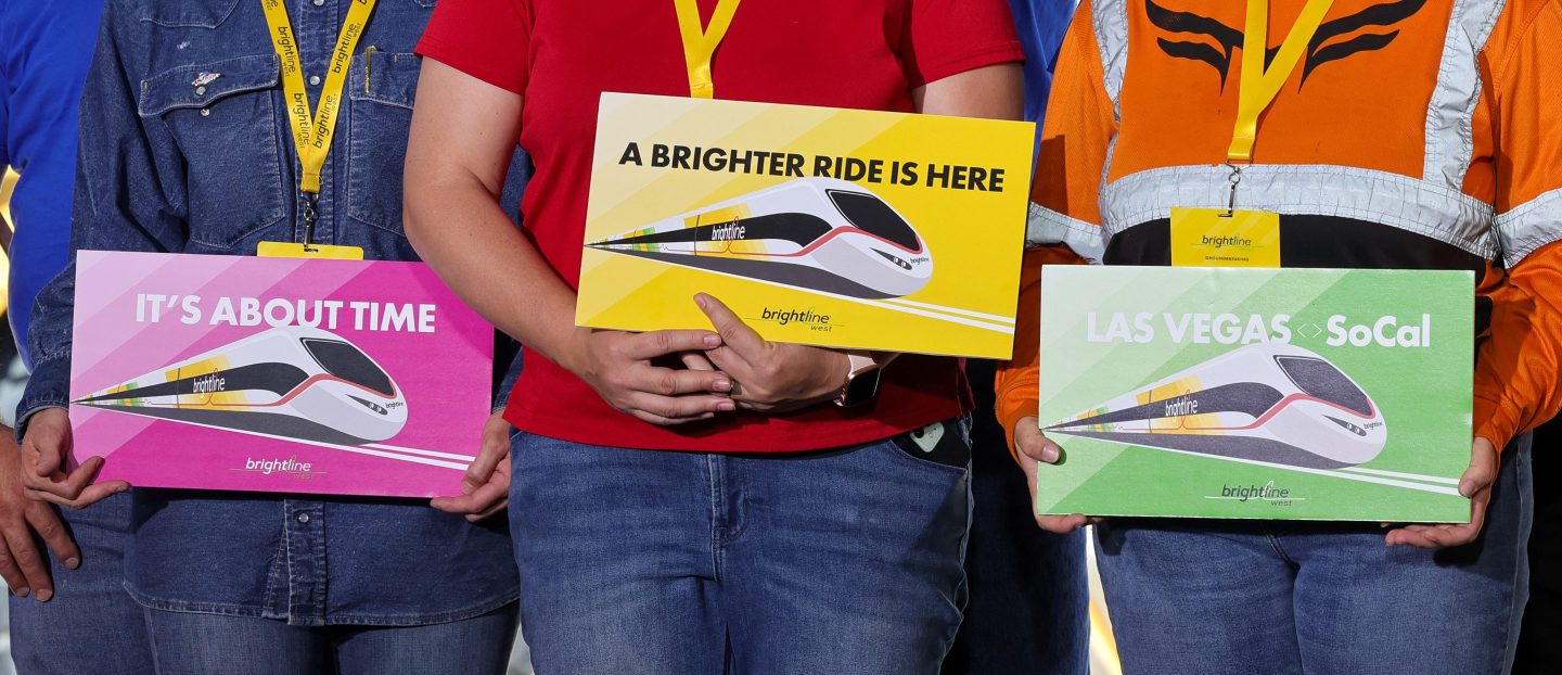 Union workers hold signs during a groundbreaking ceremony at the Brightline West Las Vegas station