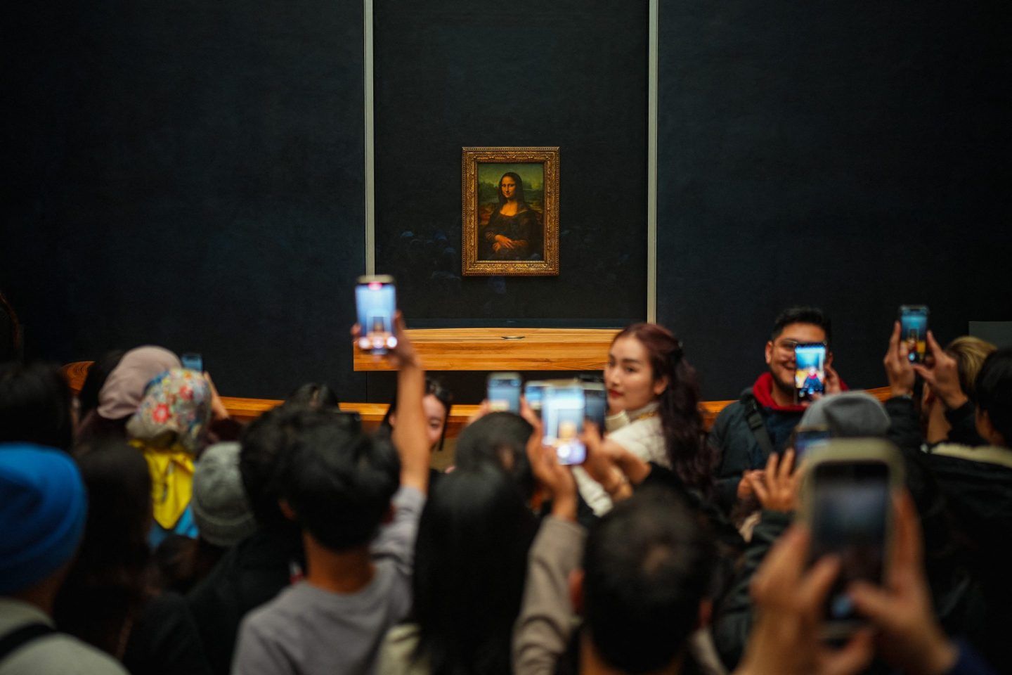 A crowd of people taking pictures of the Mona Lisa
