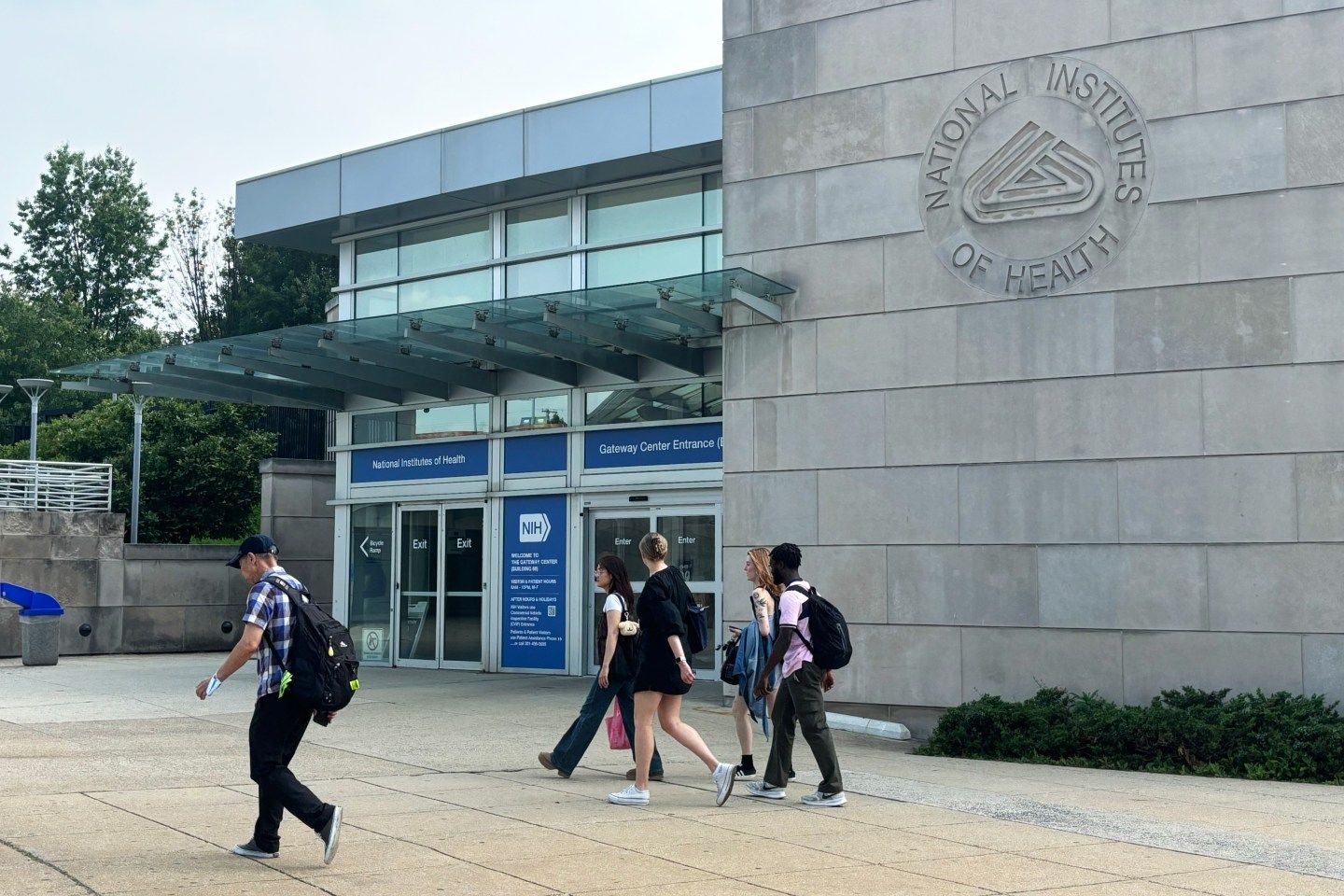 People walk past an entrance to the National Institutes of Health campus in Bethesda, Maryland, on June 5, 2025. 
