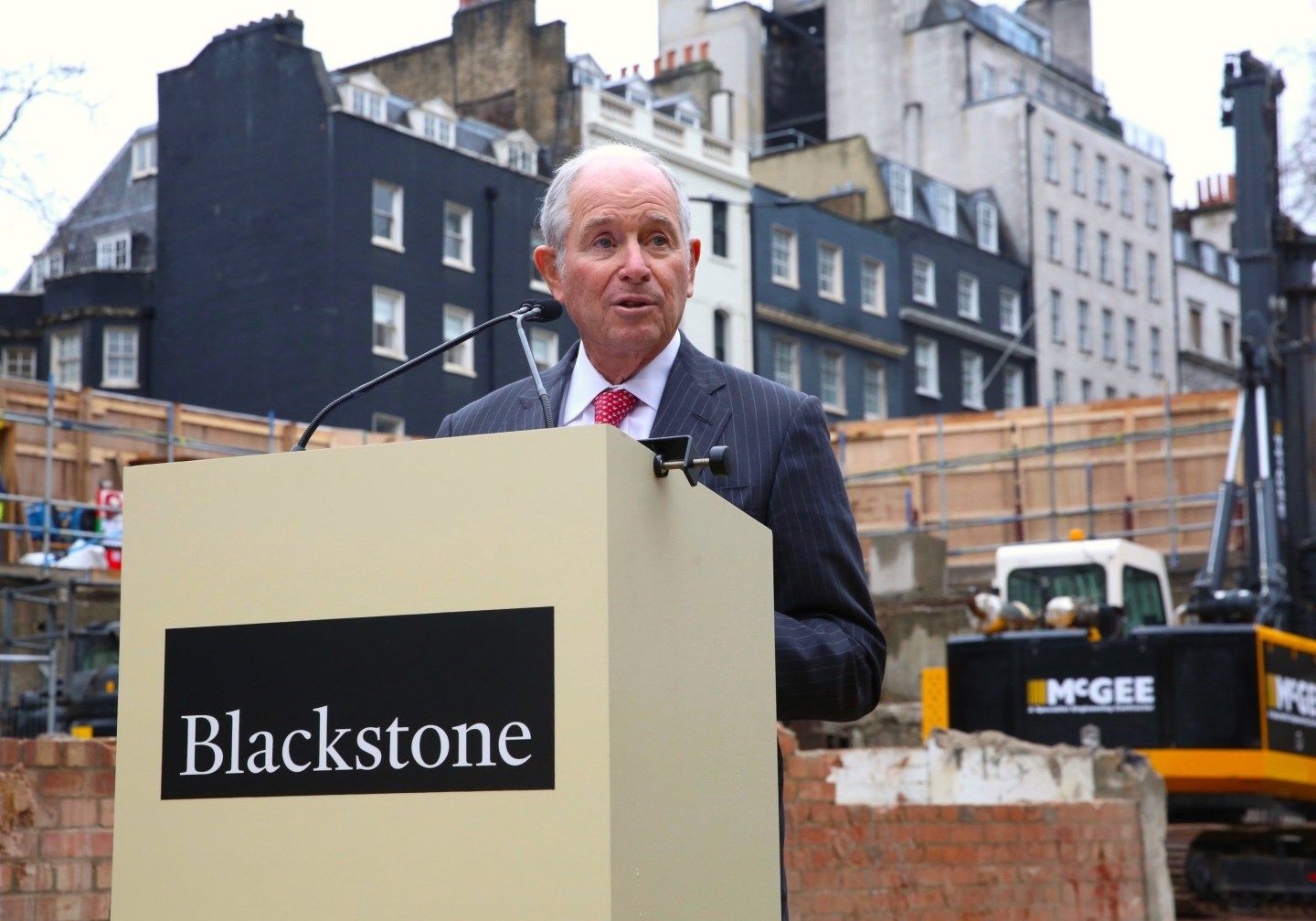 Steve Schwarzman stands in front of a Blackstone labeled podium in London.
