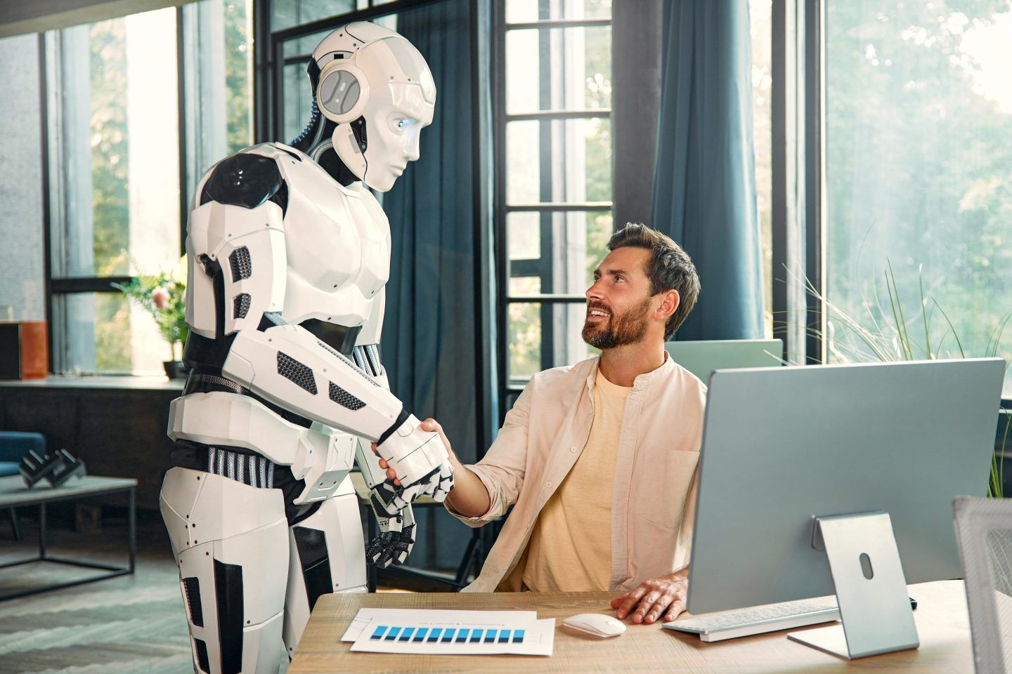 Robot assistant and young businessman working at a computer