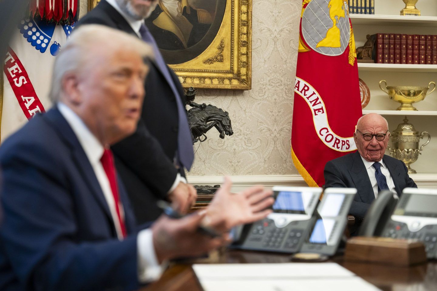 Rupert Murdoch sits in the Oval Office while Donald Trump speaks