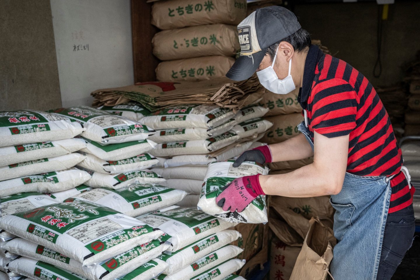 A member of staff works as bags of rice are seen piled up at a rice store in Tokyo on July 9, 2025. 
