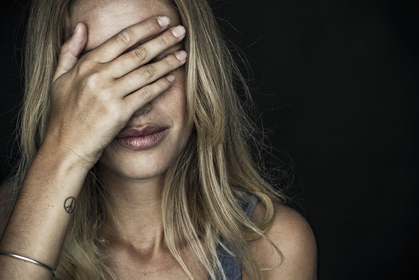 A woman covers her face with her hand.
