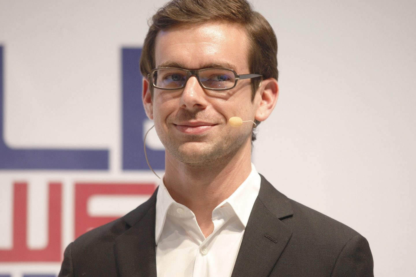 Jack Dorsey with glasses and a microphone