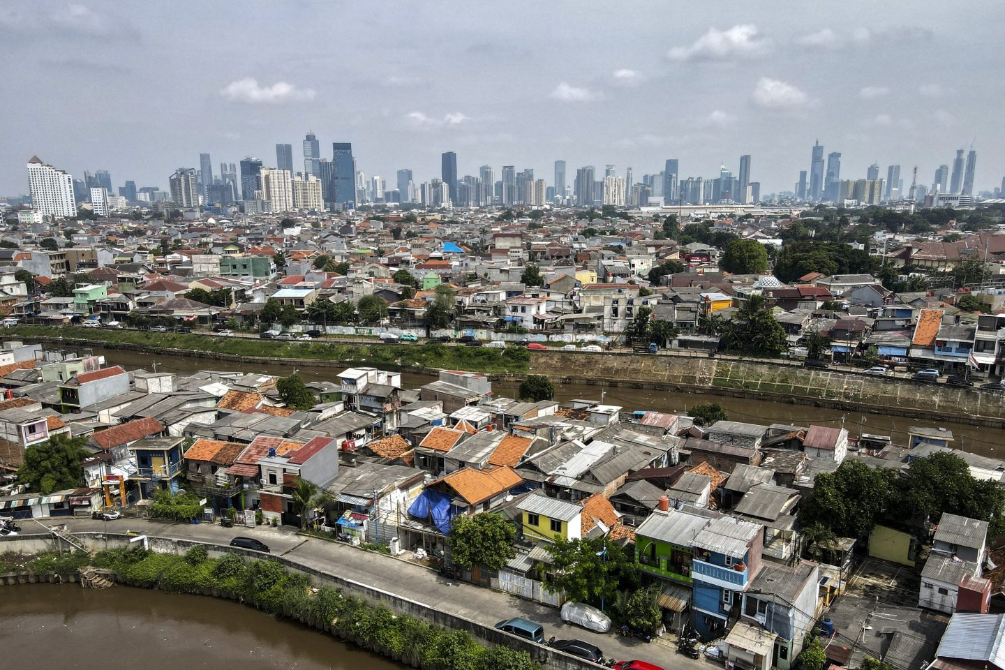 This aerial picture shows housing before the skyline of the Jakarta business district on May 9, 2025.