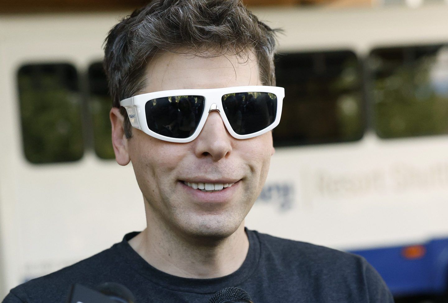 OpenAI CEO Sam Altman smiles wearing sunglasses
