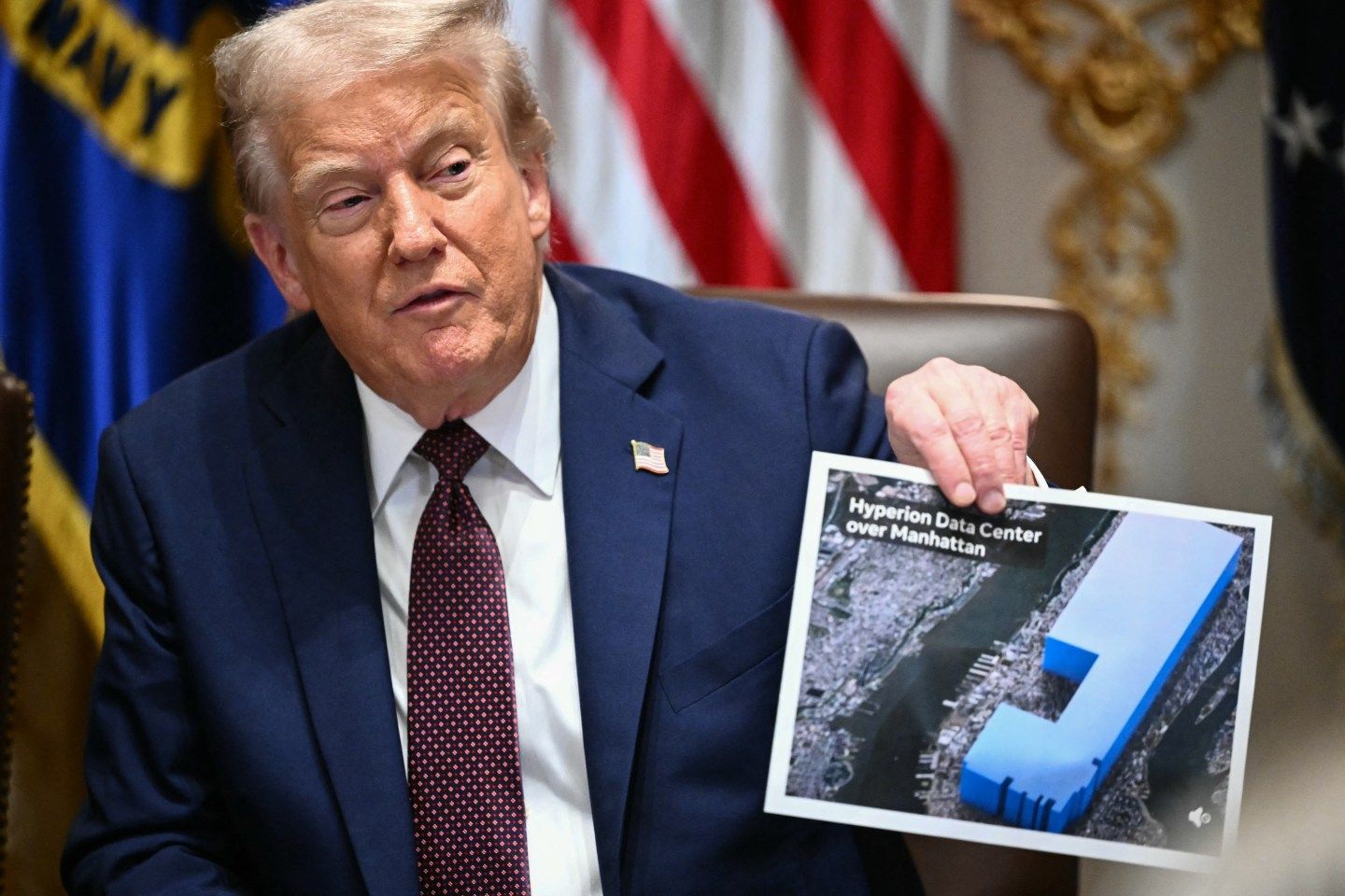 U.S. President Donald Trump holding up an aerial image of Meta's new mega-AI data center.