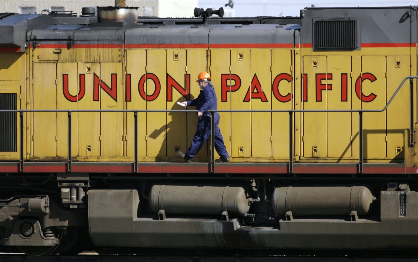 A maintenance worker walks past the company logo on the side of a locomotive in the Union Pacific Railroad fueling yard in north Denver, Oct. 18, 2006.