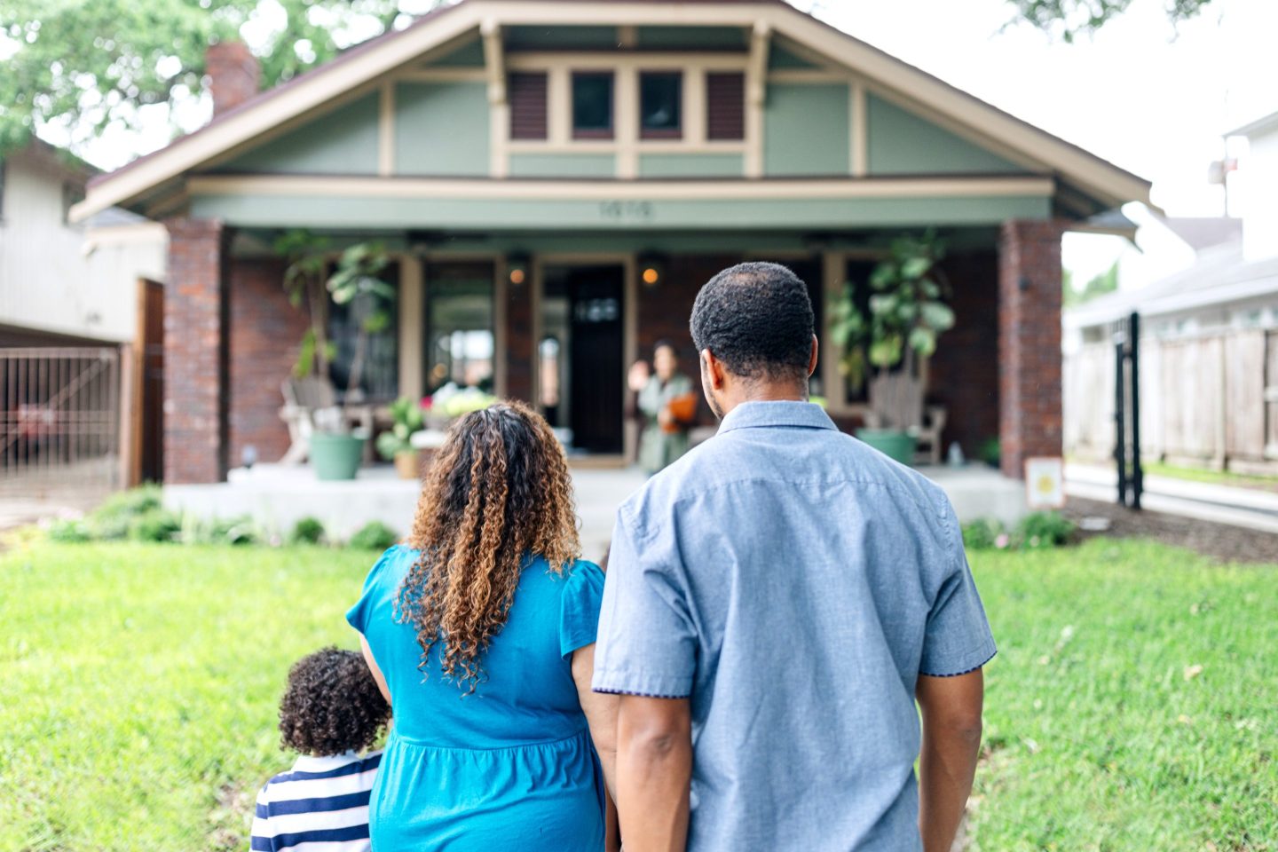 A family stands in front of home, facing it