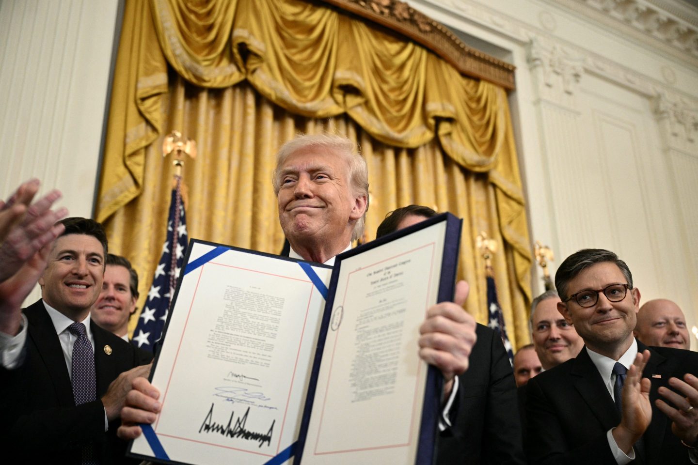 President Donald Trump displays the GENIUS Act (Guiding and Establishing National Innovation for U.S. Stablecoins Act), which codifies the use of stablecoins. 