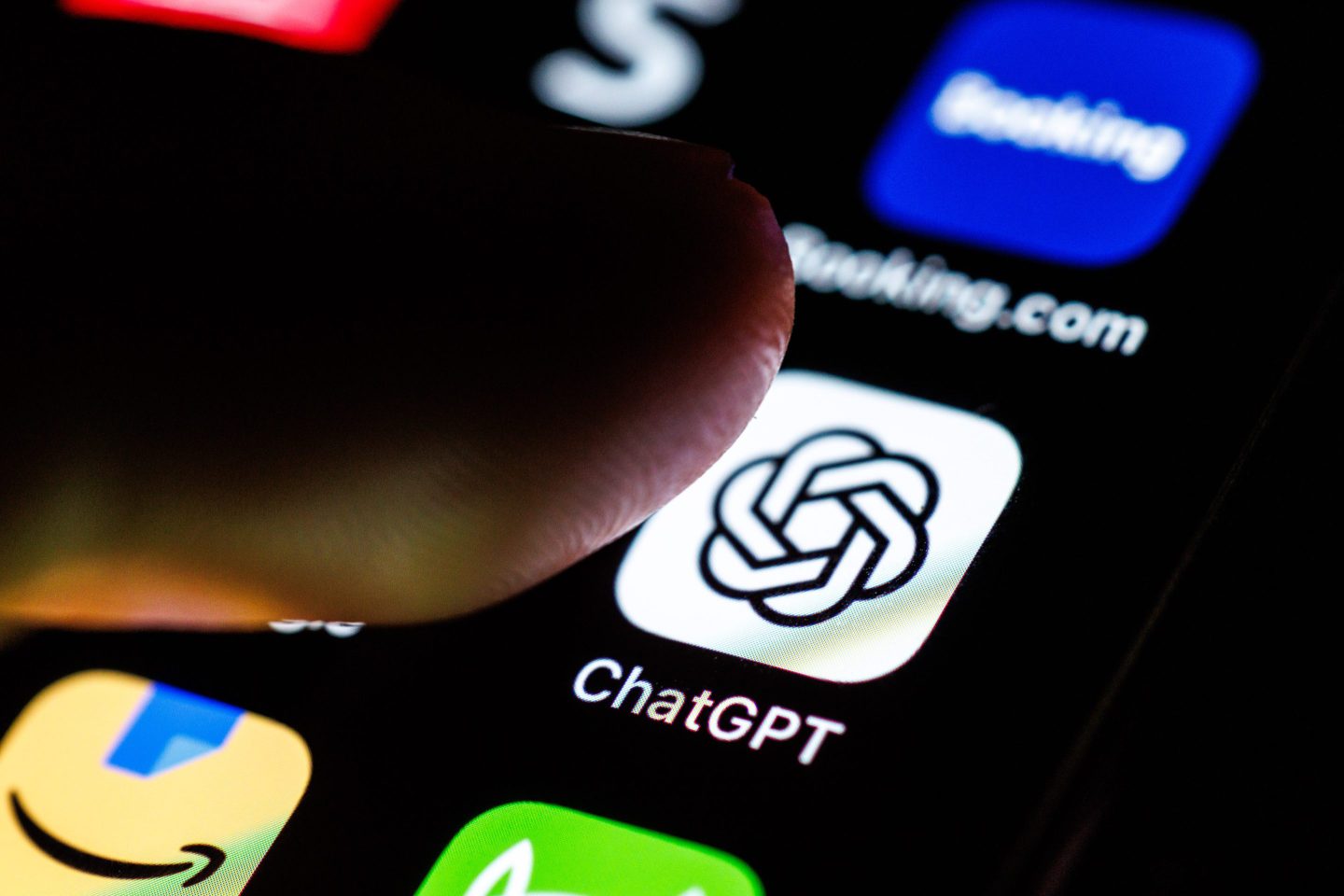 Someone's index finger poised over the ChatGPT app icon on the touchscreen of a smartphone.