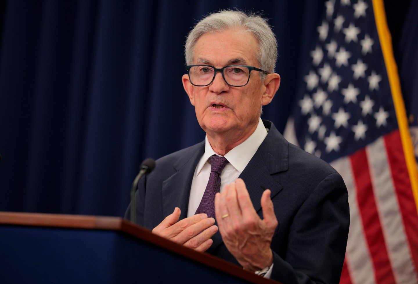 Federal Reserve Chair Jerome Powell in a dark suit at a podium.