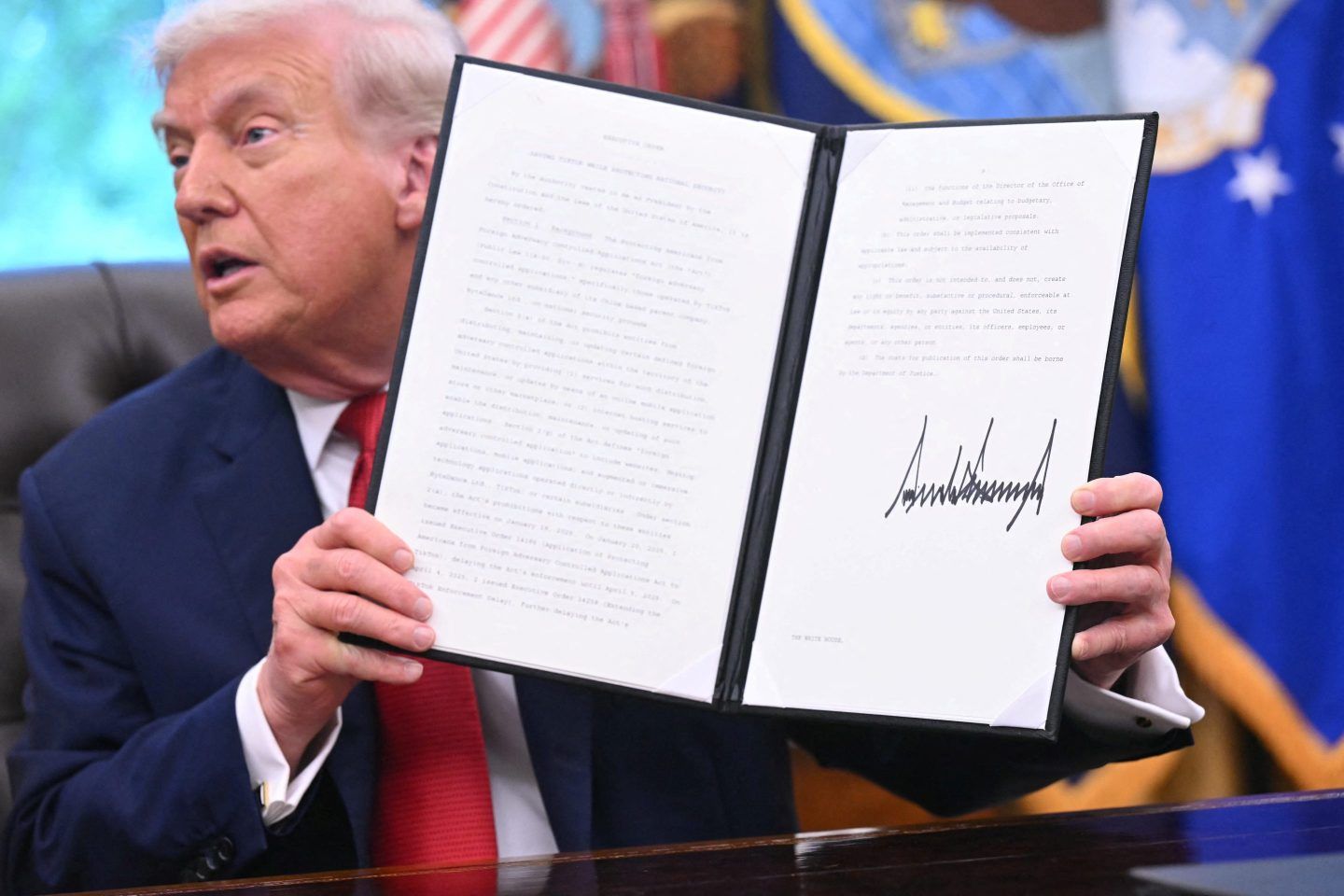 US President Donald Trump shows an executive order about Tiktok he signed in the Oval Office of the White House in Washington, DC, on September 25, 2025.