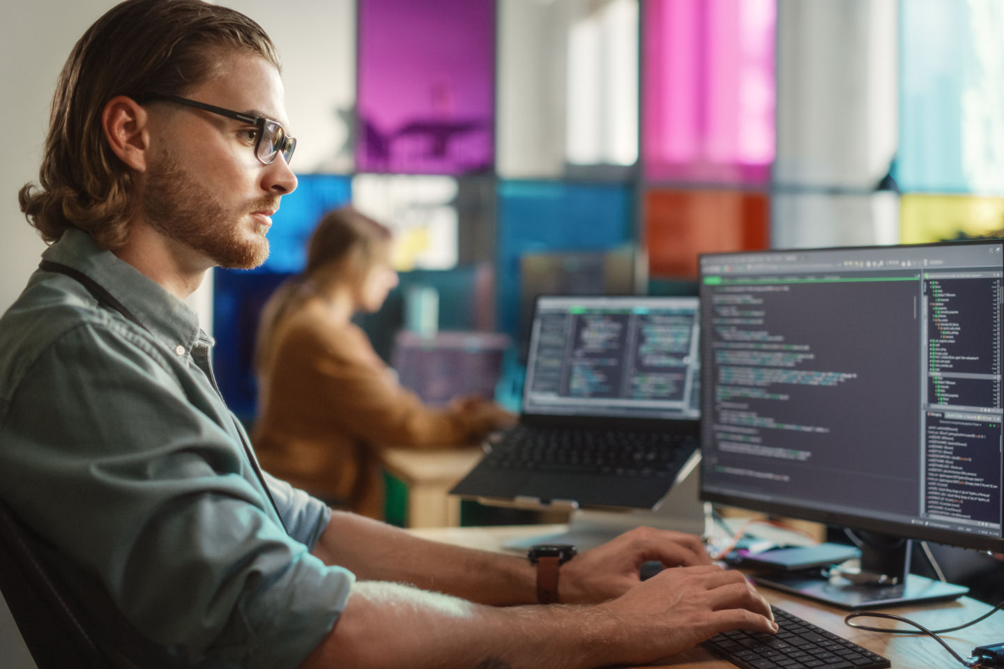 Software engineer at desk in front of computers