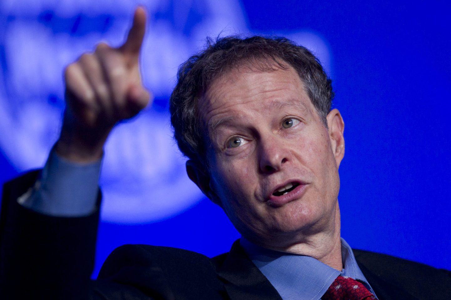 Former Whole Foods CEO John Mackey speaks on stage while lifting his hand