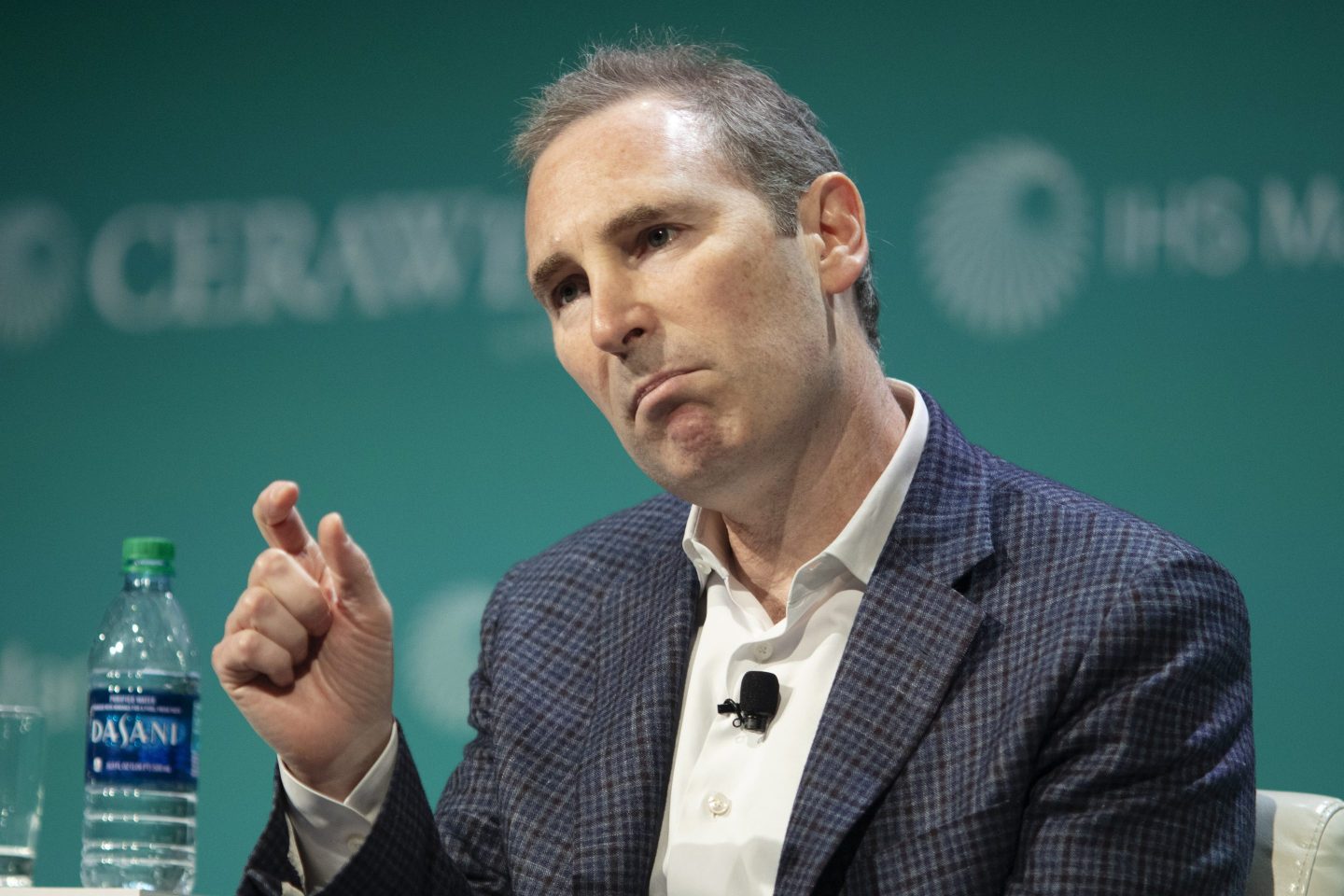 Andy Jassy sits and holds up his fingers as if to describe how small something is