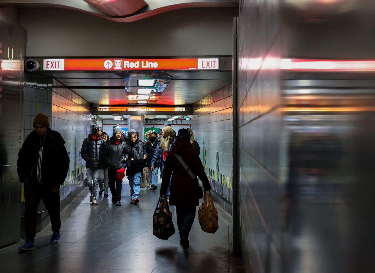Riders walk to and from the Red Line stop in the Roosevelt CTA station on Dec. 19, 2023, in Chicago.