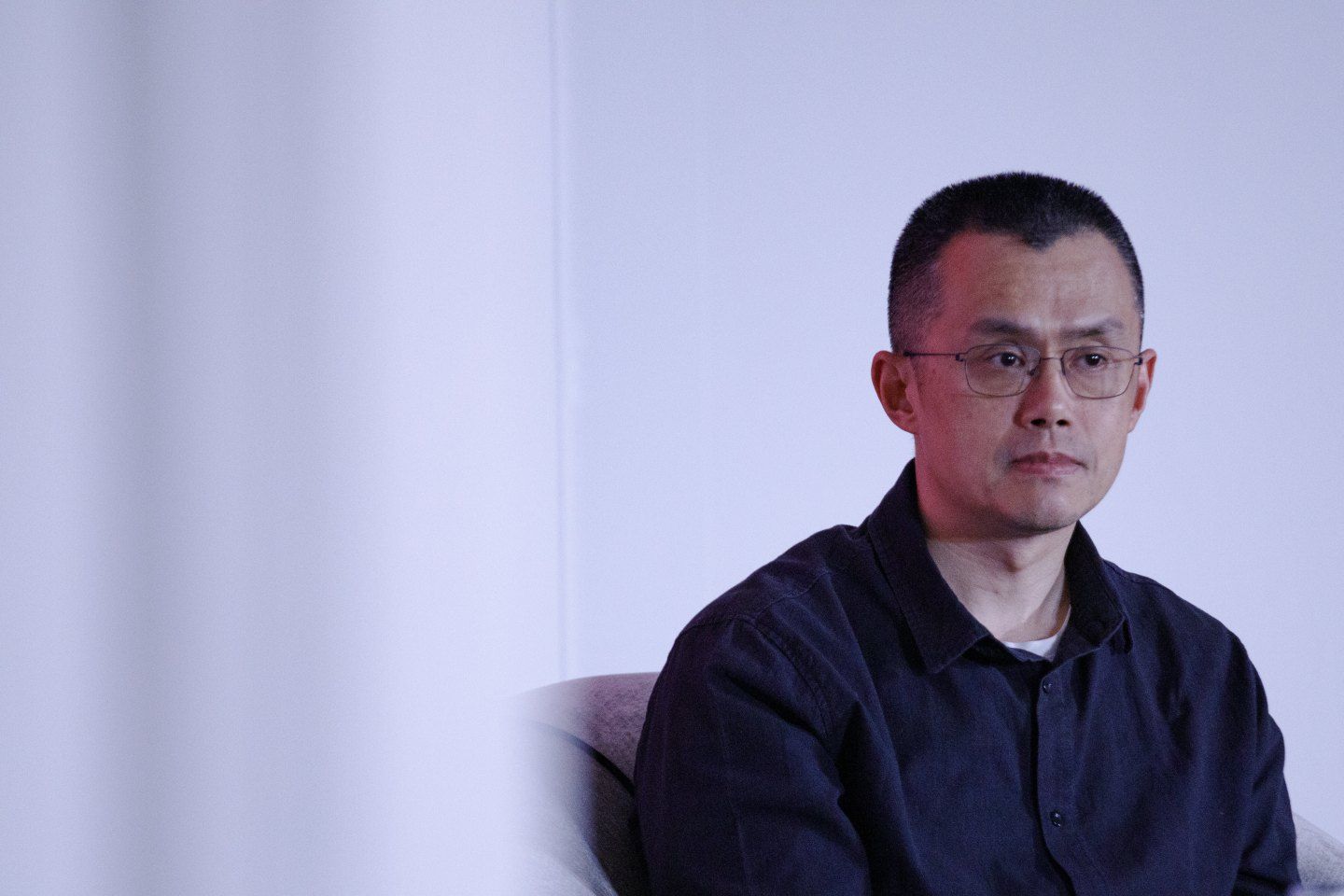 Changpeng Zhao looks of camera in front of blank wall.