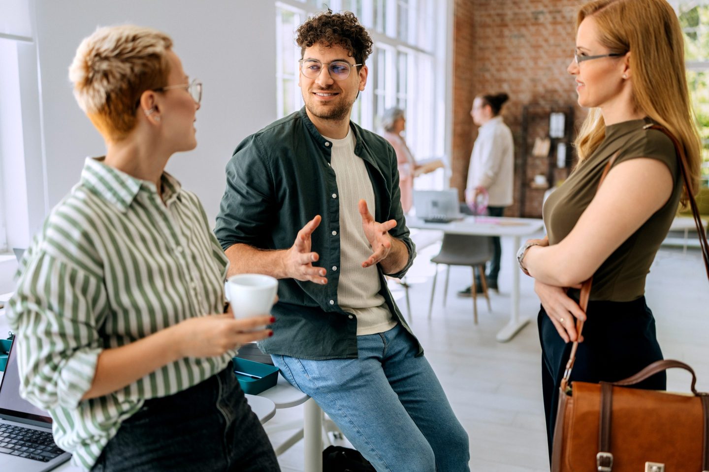 Three young professionals talk together in an office.